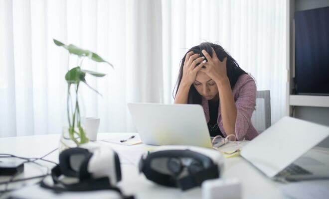 Ragazza davanti a un computer, visibilmente stressata, con mani tra i capelli