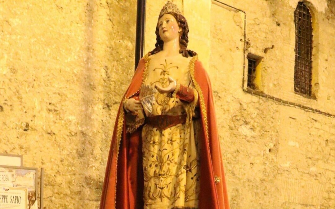 statua Santa Giustina durante una processione. intorno a lei persone radunate