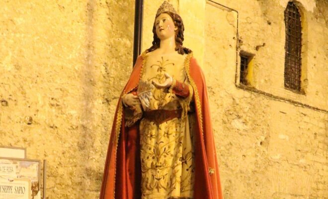 statua Santa Giustina durante una processione. intorno a lei persone radunate